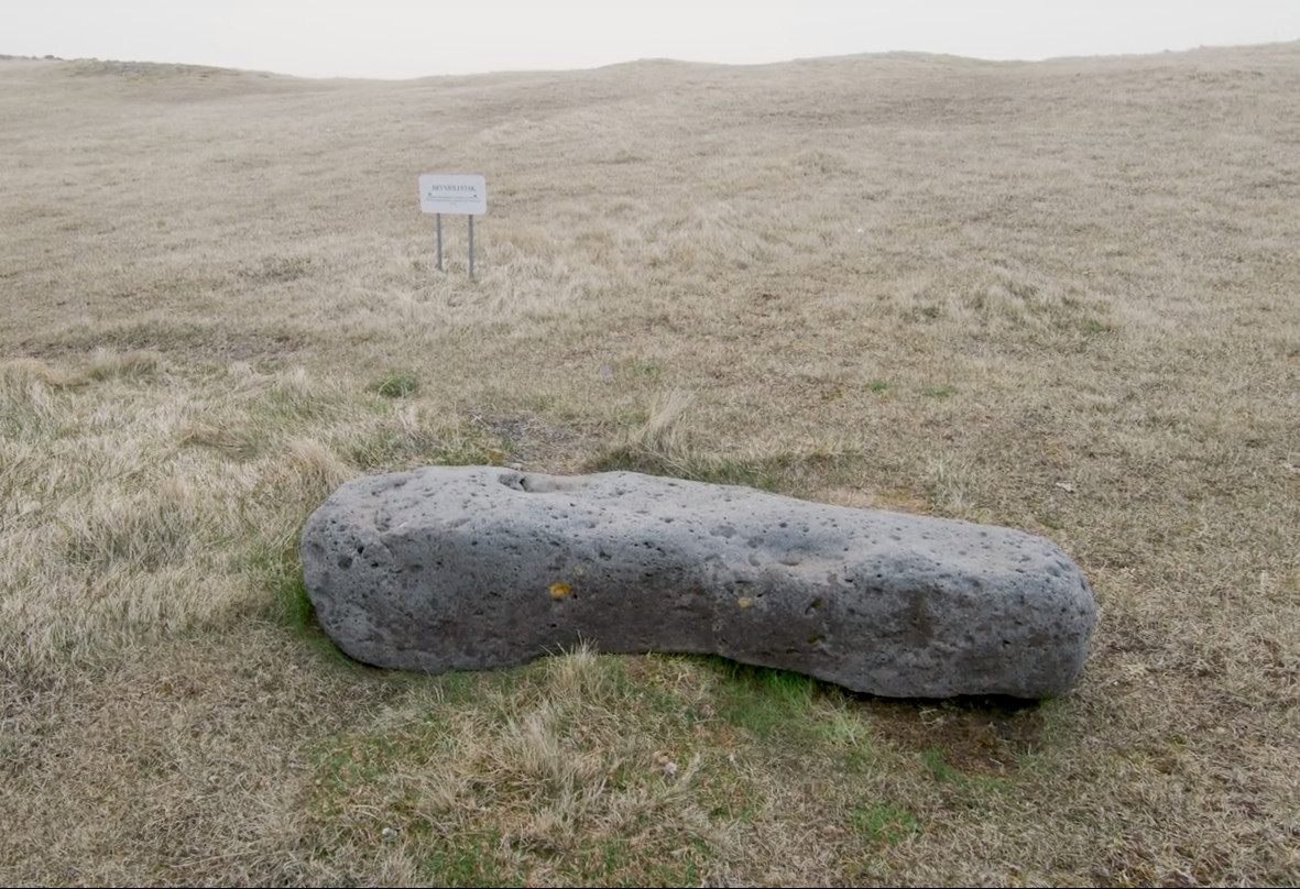 A photo of a long, heavy stone lying on its side.